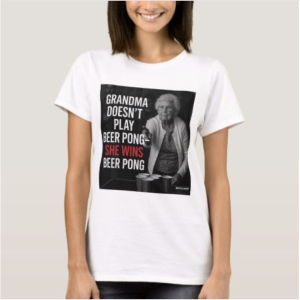 A bold graphic T-shirt featuring a cartoon-style grandma dominating a game of beer pong, surrounded by red solo cups and a smirk that says she’s the life of the party. Text reads: She’s the reason the HOA banned block parties 👵. Edgy, funny, and rebellious design for moms, grandmas, or anyone with a wild streak.