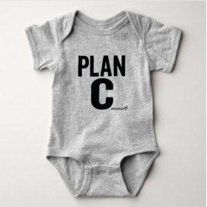 White baby onesie printed with bold black text that reads “PLAN C” with the mom.wtf logo underneath, designed as a funny unisex outfit for boys or girls.