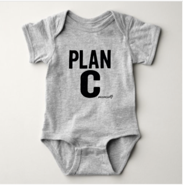 White baby onesie printed with bold black text that reads “PLAN C” with the mom.wtf logo underneath, designed as a funny unisex outfit for boys or girls.